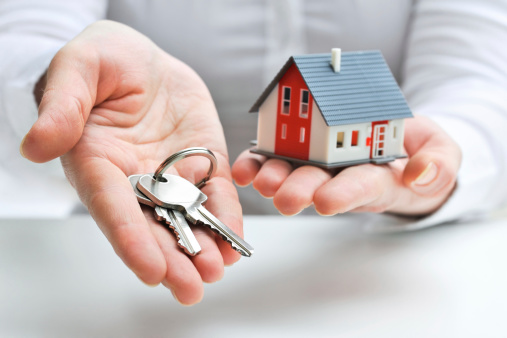 a man holding a key and house toy